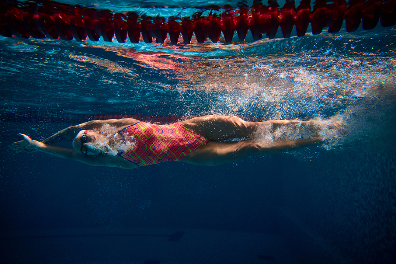 A woman competitive swimmer swims under water.