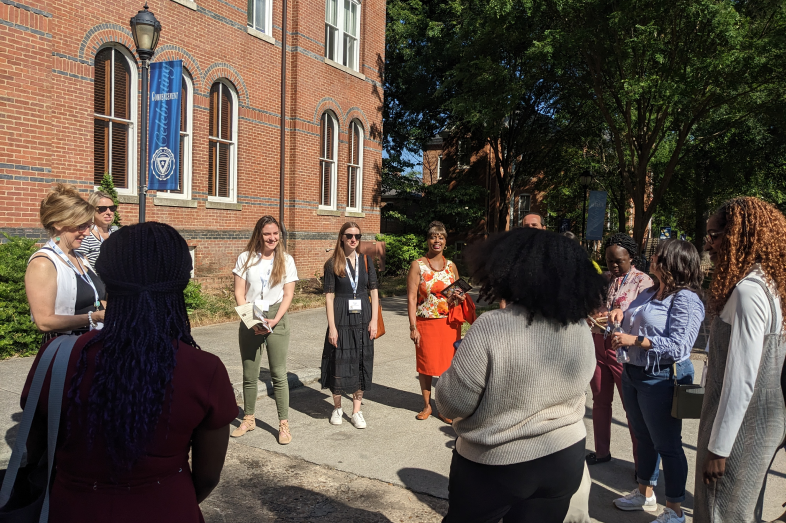 A group of people stand on the campus of Spelman University in a circle.