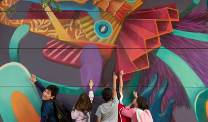 Five children touch the paint of a colorful mural.