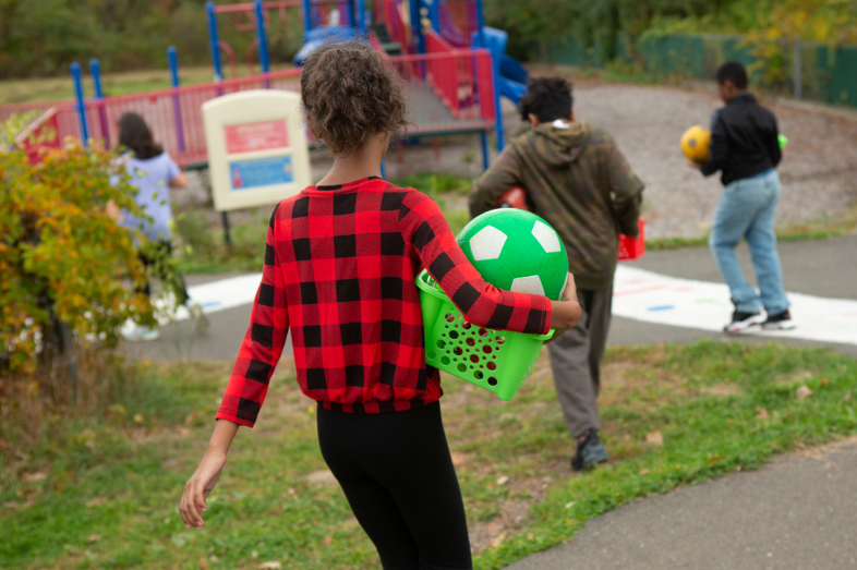 Kids playing outdoors are shown from behind.