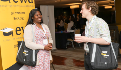 A Black woman and a white man face each other as they speak to each other at a conference.