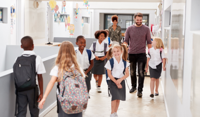 Students in uniforms walk in their school hallway.