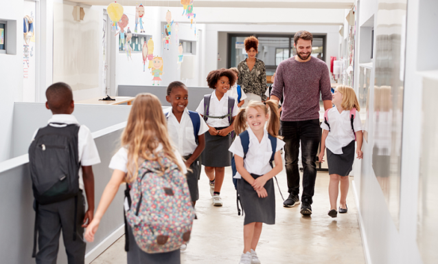 Students in uniforms walk in their school hallway.