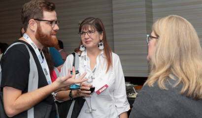 Three people talk at a networking event.