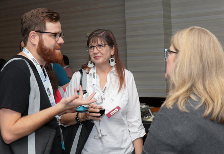 Three people talk at a networking event.