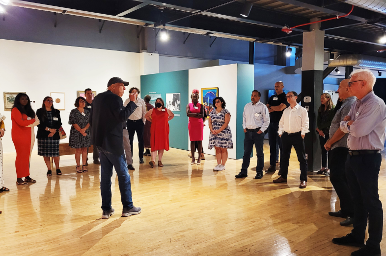 A group of people stand in a circle around a speaker.