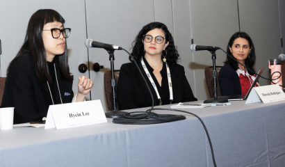 Three women panelists sit at a table with microphones before them.