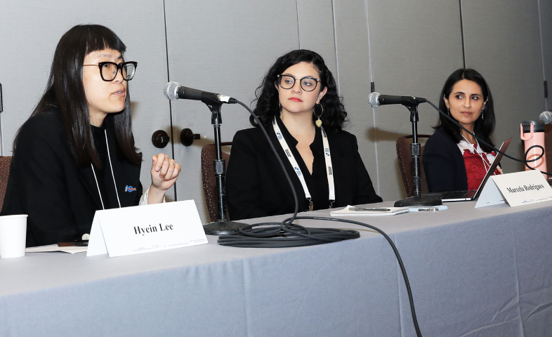 Three women panelists sit at a table with microphones before them.