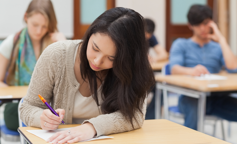 A young woman takes an exam at a desk.