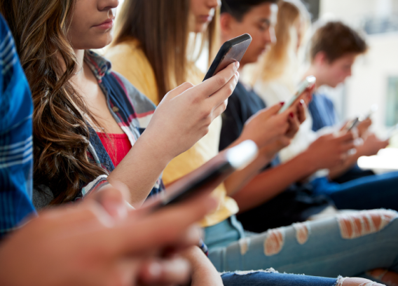 A group of students on their cell phones ignore each other.