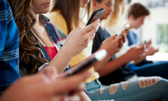 A group of students on their cell phones ignore each other.