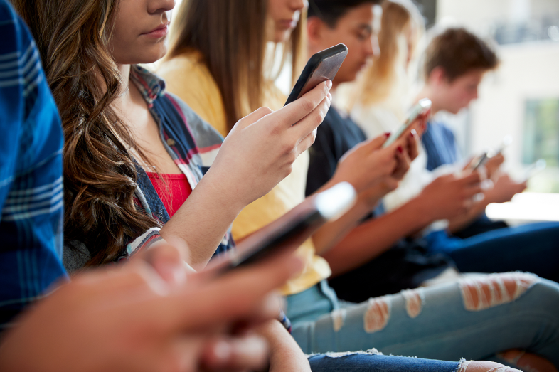 A group of students on their cell phones ignore each other.