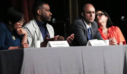 Four speakers sit at a table discussing major issues.