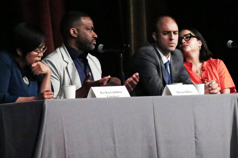 Four speakers sit at a table discussing major issues.