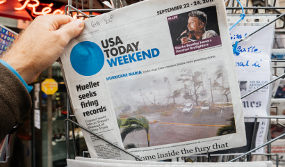 A newspaper's front page shows an article about Hurricane Maria.