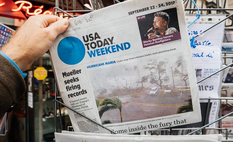 A newspaper's front page shows an article about Hurricane Maria.