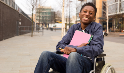 A Black young male student in a wheelchair, smiles