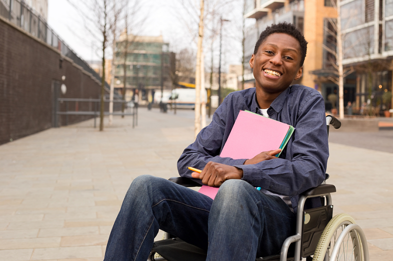 A Black young male student in a wheelchair, smiles