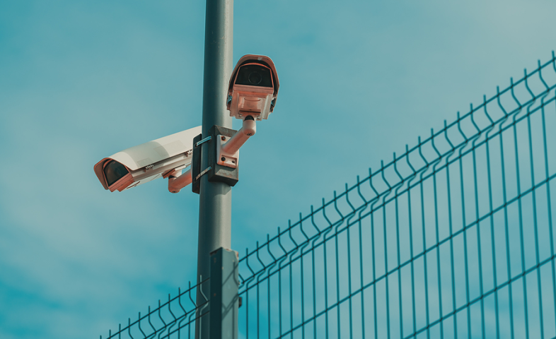 Two surveillance cameras mounted to a pole point in opposite directions.