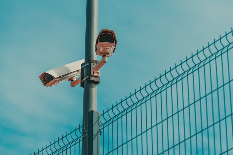 Two surveillance cameras mounted to a pole point in opposite directions.