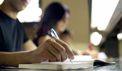 A male student writes in his notebook.