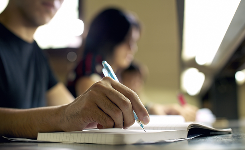 A male student writes in his notebook.