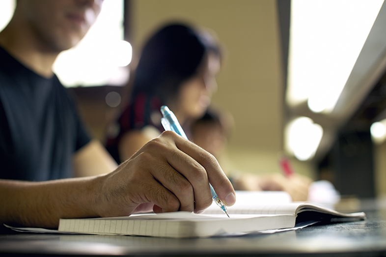 A male student writes in his notebook.