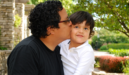 A father kisses his child on the cheek.