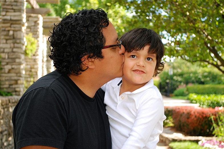 A father kisses his child on the cheek.