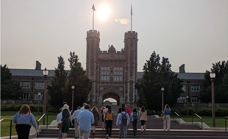 A group of people climb stairs on the campus of a university.