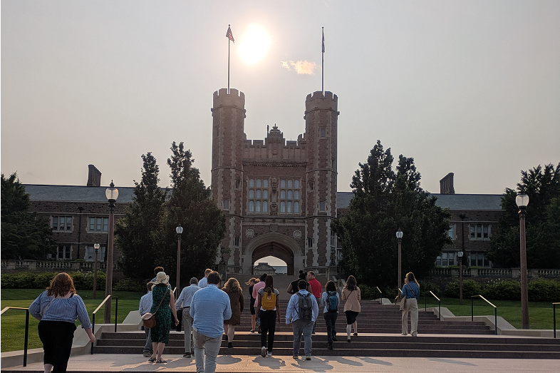 A group of people climb stairs on the campus of a university.