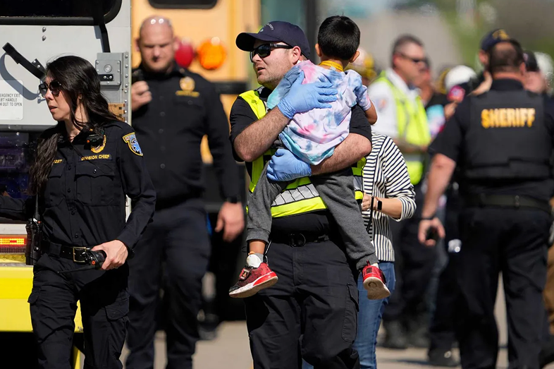 A first responder carries a boy after a school bus crash.
