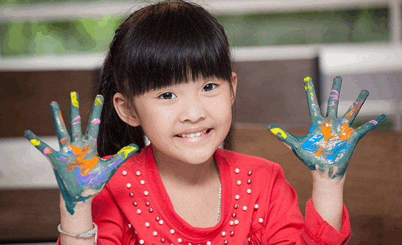 Cute Asian preschooler with paint on her hands.