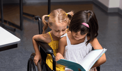 A little girls sits on the lap of a wheelchair bound girl.