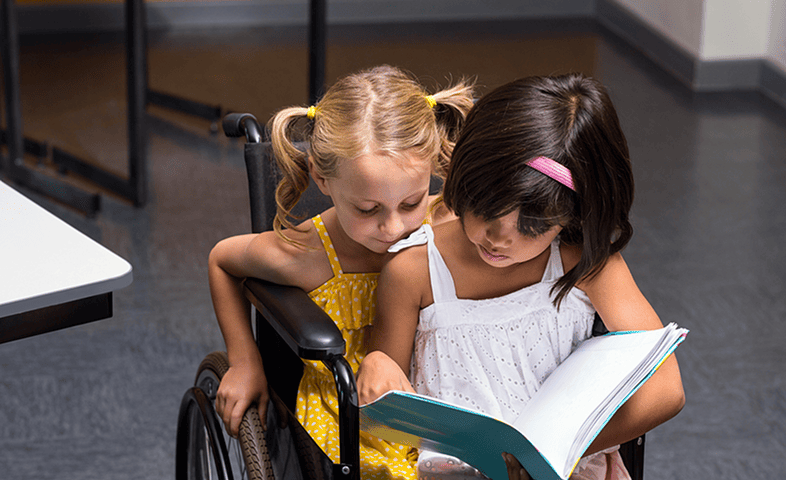A little girls sits on the lap of a wheelchair bound girl.