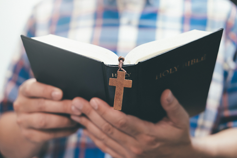 An unidentified man holds and reads a Bible.