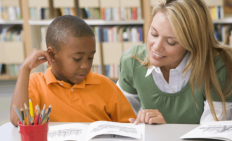 A teacher helps a student with reading.