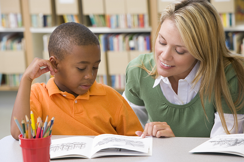 A teacher helps a student with reading.
