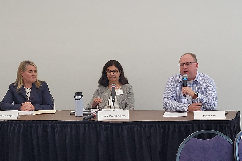 Two women and a man on a speaker panel.