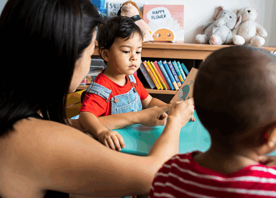 A woman teaches a young child to read.