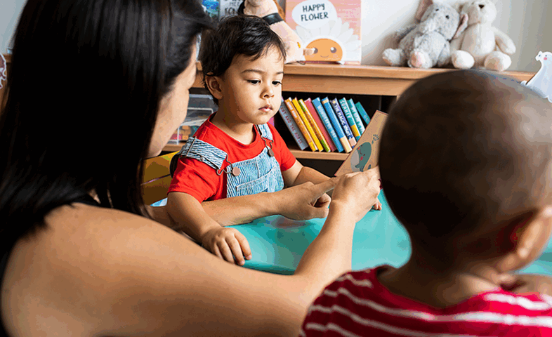 A woman teaches a young child to read.