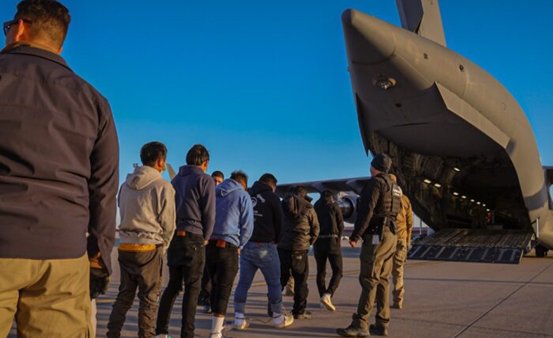 Men stand in line to board a flight.