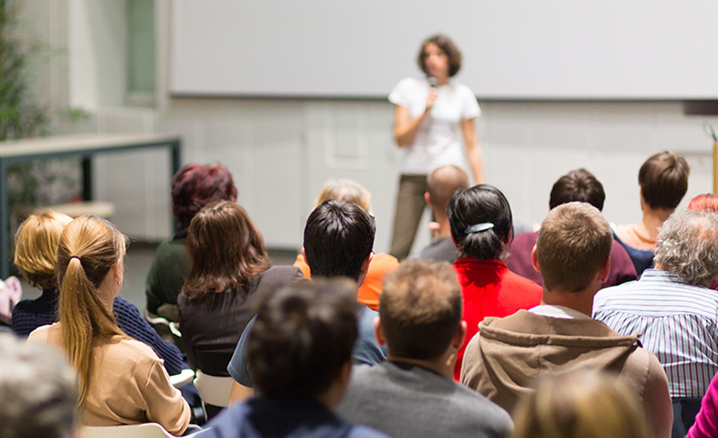 A woman speaker gives a presentation in a lecture hall at a university.