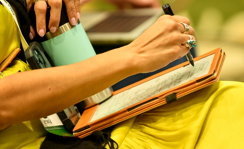 A woman writes on a digital tablet.